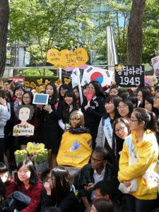 A rally of people, some of them holding yellow signs and wearing yellow jumpers.